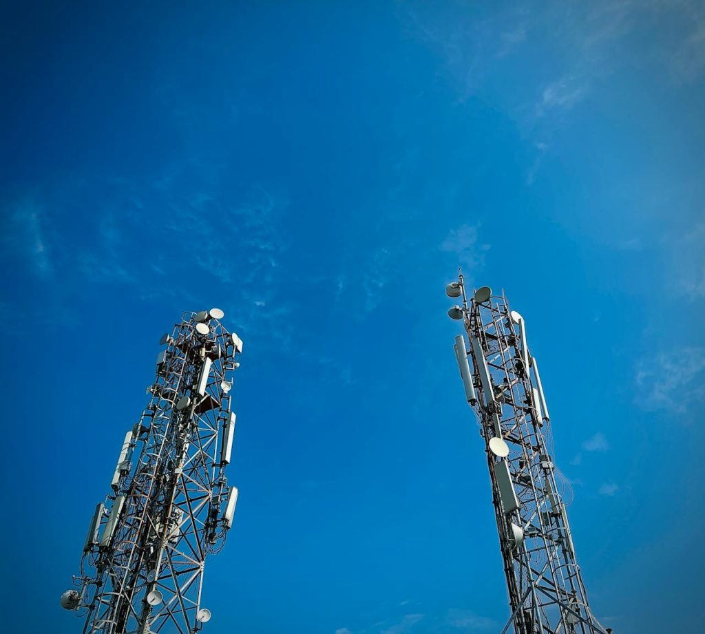Two telecommunication towers standing against a vibrant clear blue sky, showcasing modern communication technology.